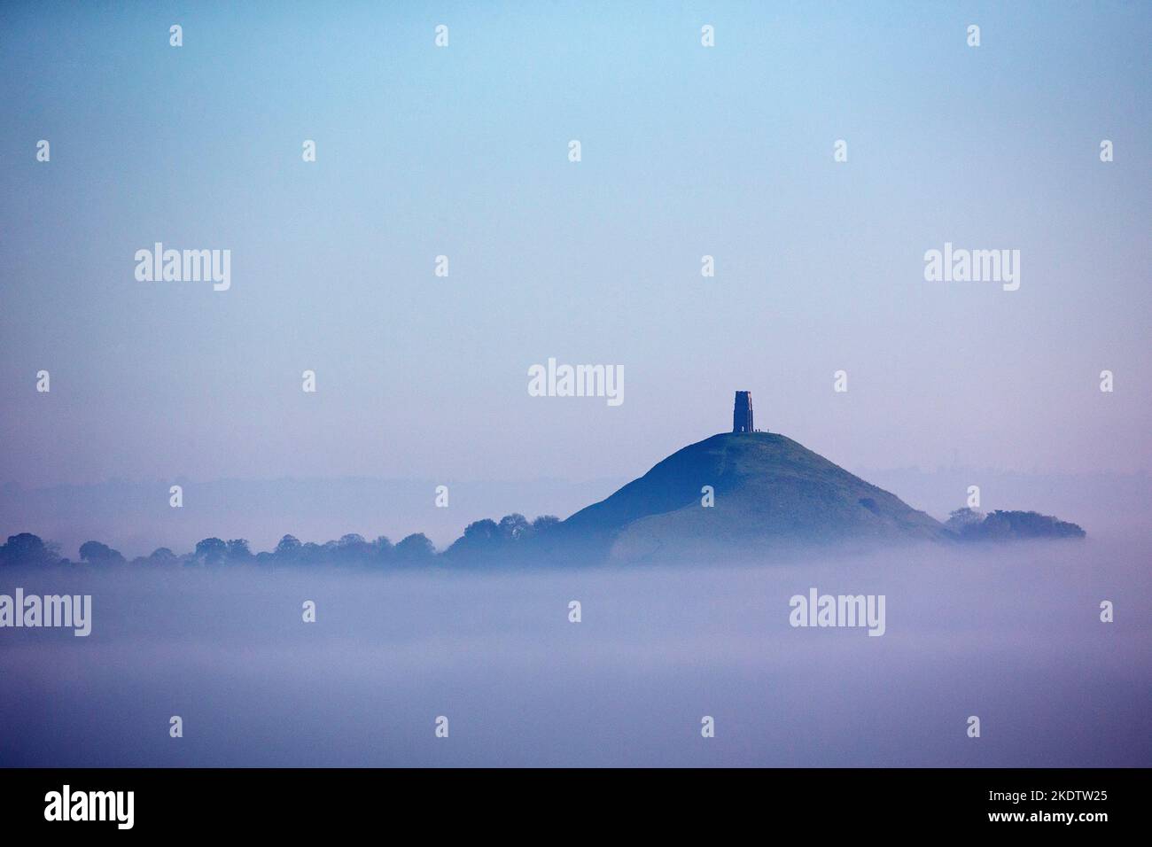 Glastonbury Tor and St Michael's Tower with the town of Street in early morning mist from Walton Hill, Somerset, England, UK, October 2018 Stock Photo