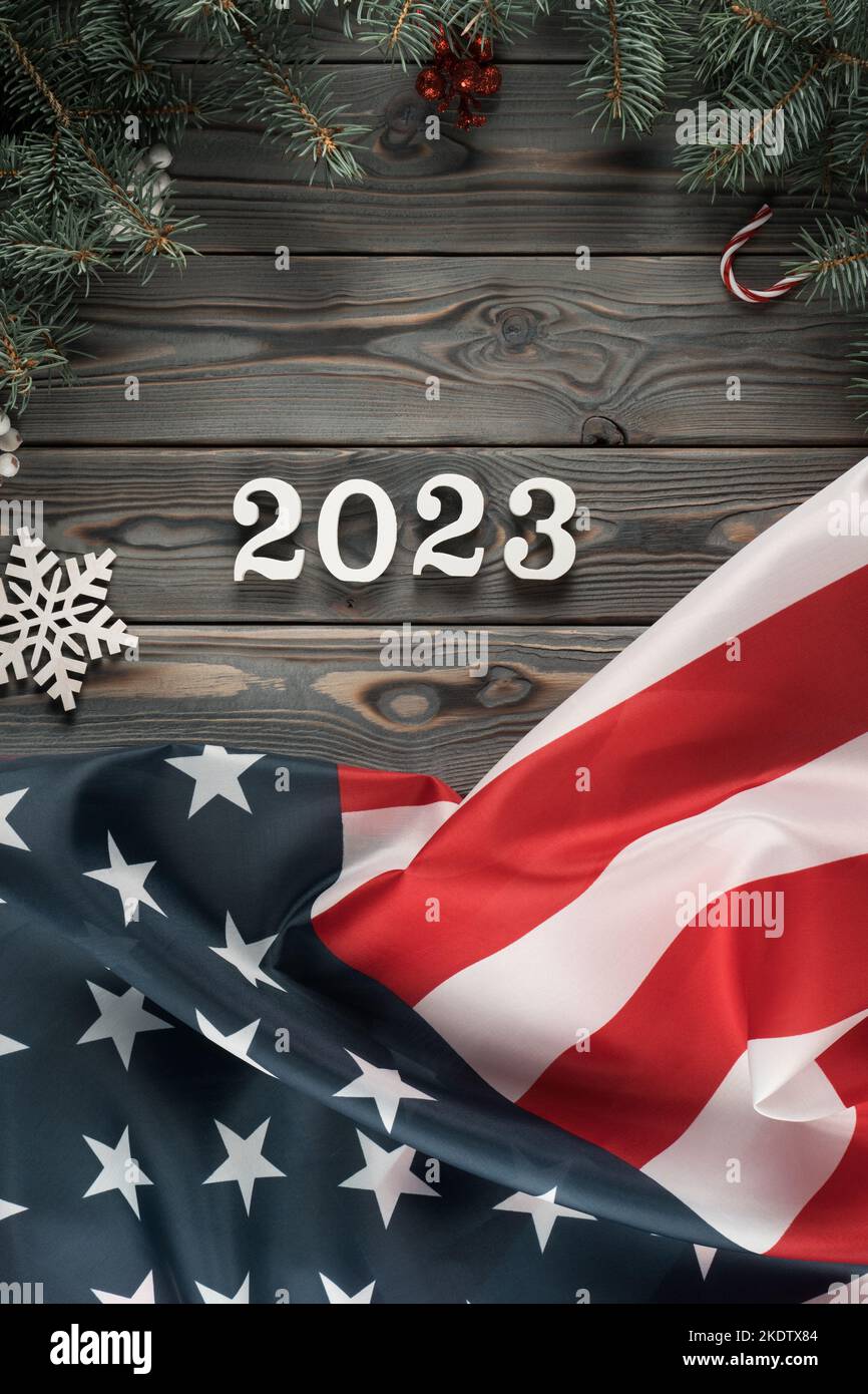 Vertical dark wooden wallpaper with American flag 2023 and Christmas toy frame decoration. Happy new year and merry xmas. Green card emigration and Stock Photo