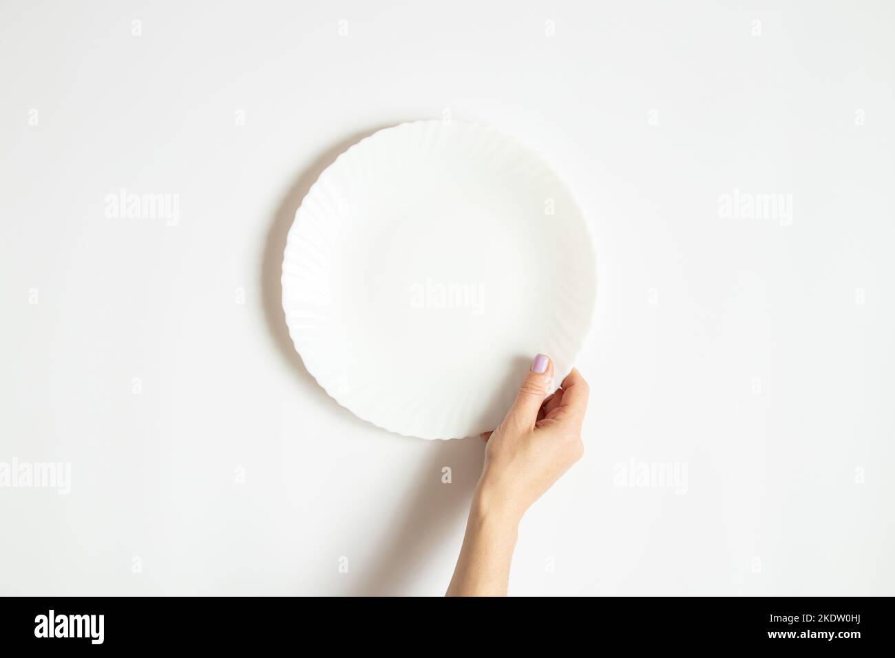 White clean plate in the hands of a girl on a white background close-up Stock Photo