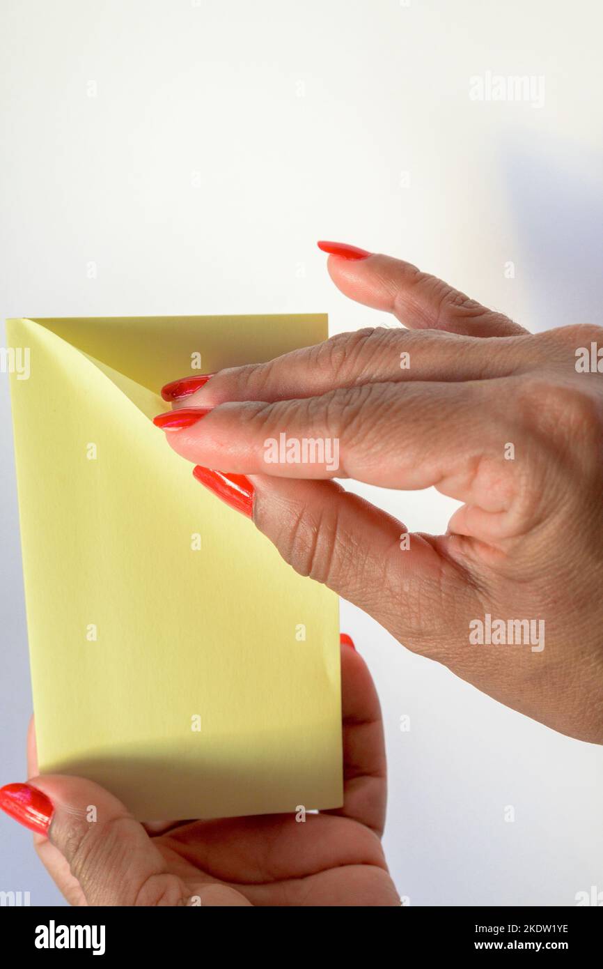 Woman's hand with painted nails holding blank letter paper on pure