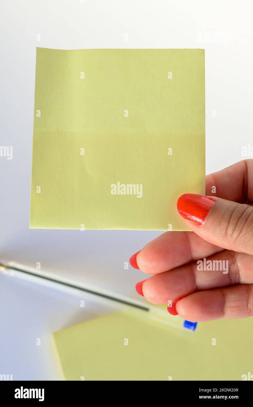 Woman's hand with painted nails holding blank letter paper on pure