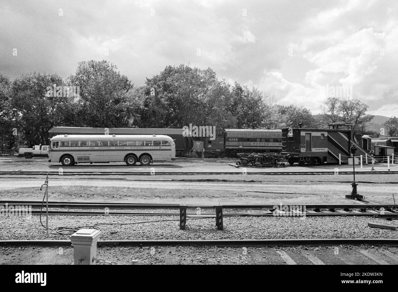 A vintage school bus and varios retired railroad cars parked along the tracks at the Conway Scenic Railroad station in North Conway, New Hampshire. Th Stock Photo