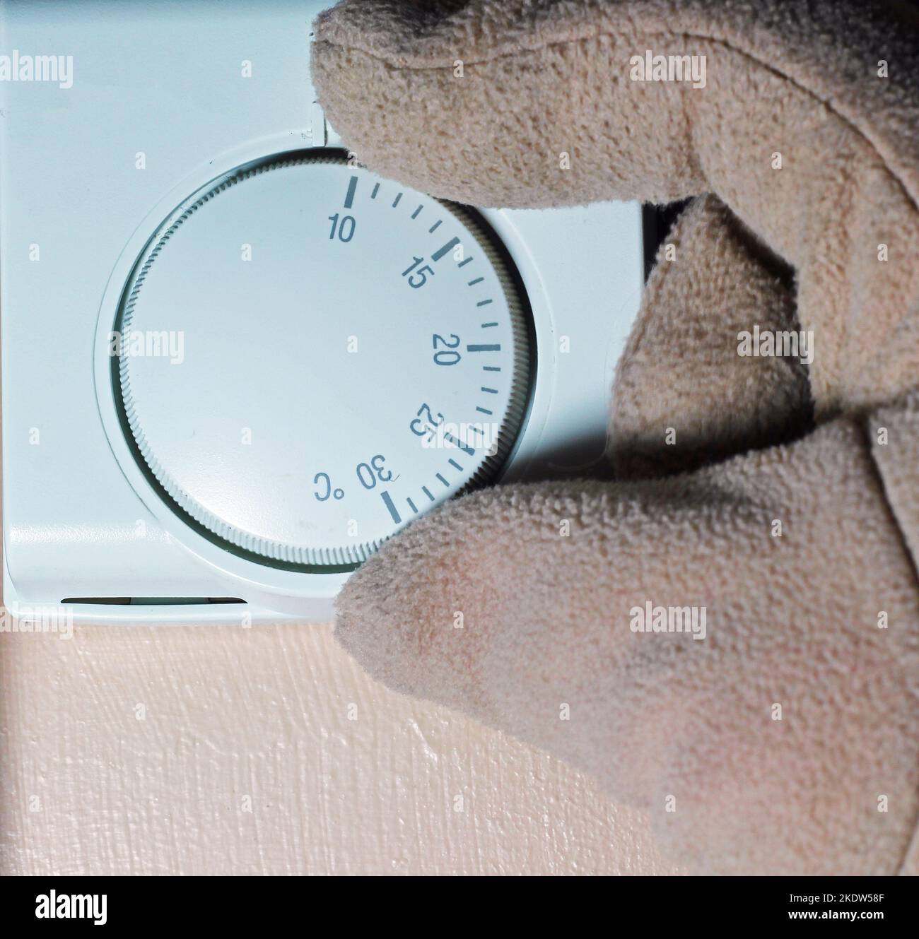 Turning down the central heating thermostat with a gloved hand. Cold