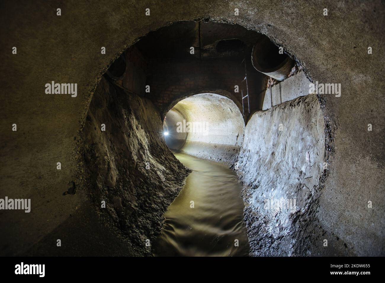Inside underground urban sewer system. Sewage flowing in round sewer