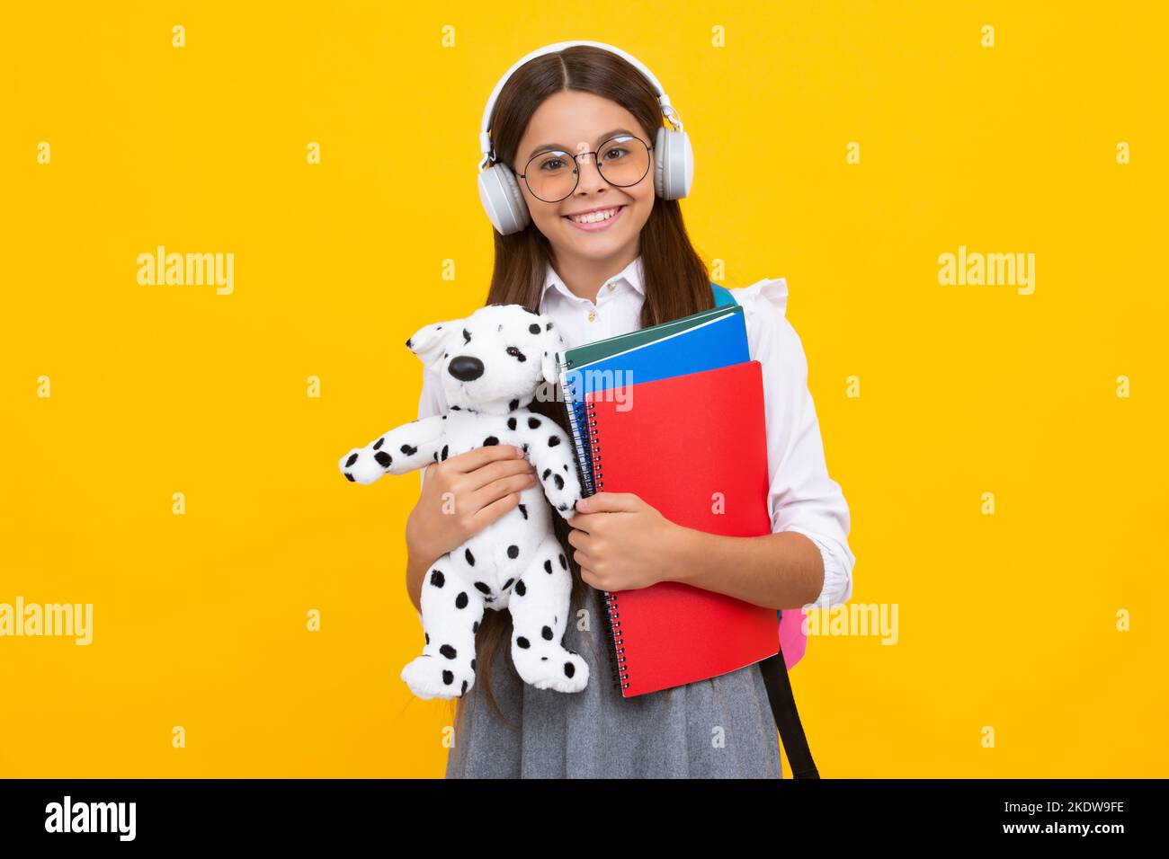 Schoolgirl 12, 13, 14 years old with toy. School children cuddling favorite toys on yellow background. Happy childhood. Happy girl face, positive and Stock Photo