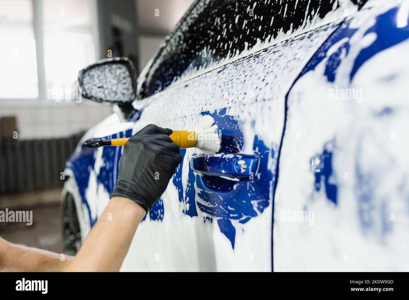 Hand brush washing of car body with foam in car detailing service. Car