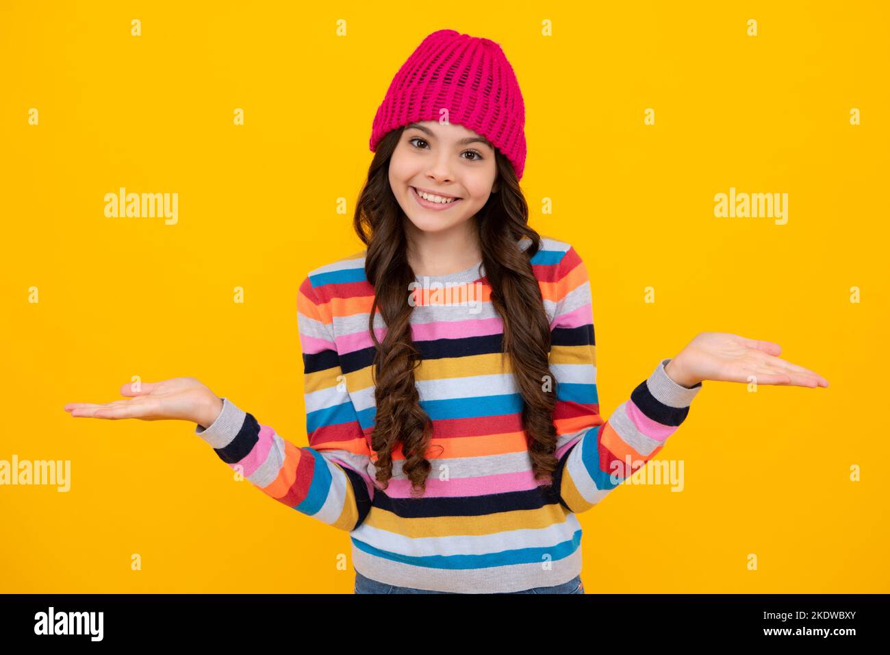 Modern teenage girl 12, 13, 14 year old wearing sweater and knitted hat on isolated yellow