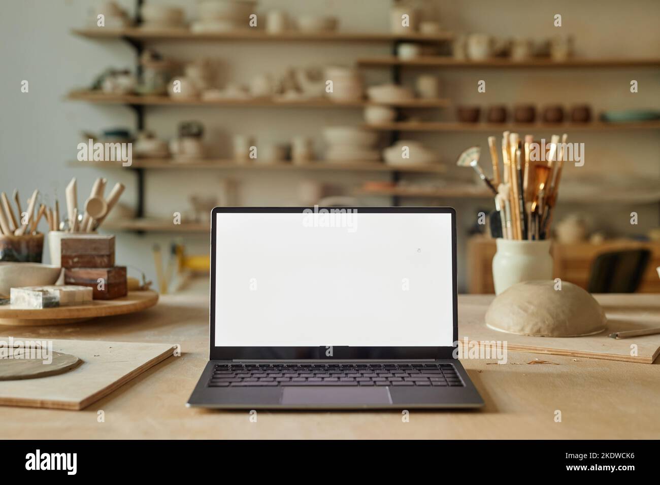 Background image of opened laptop with blank white screen in pottery workshop, copy space Stock Photo