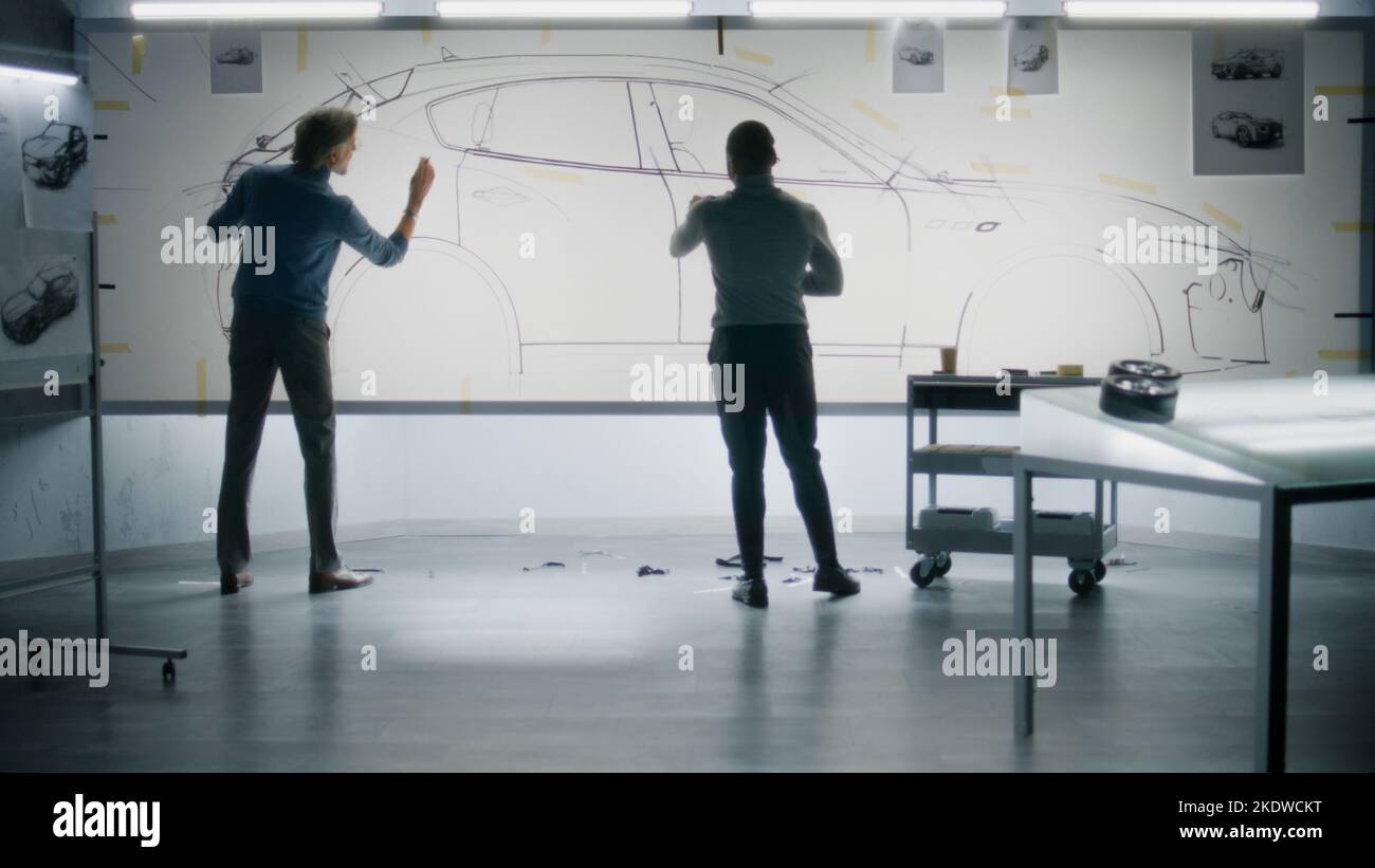 Two diverse automotive male designers drawing sketch with marker on