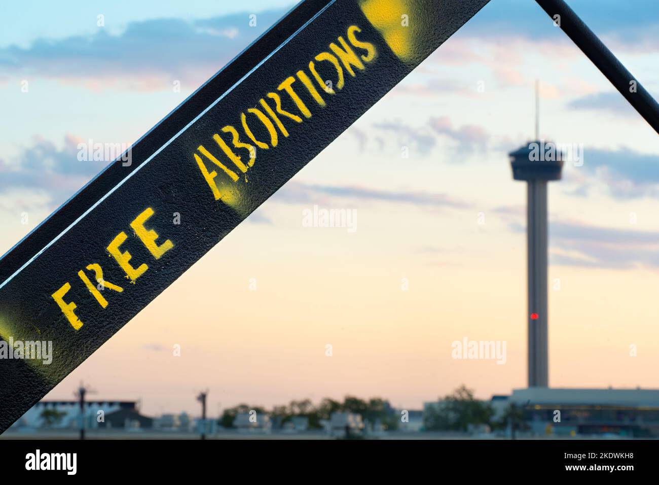 Graffiti that states 'FREE ABORTIONS' on the Hays Street Bridge in San Antonio, Texas, with the Tower of the Americas visible in the background. Stock Photo