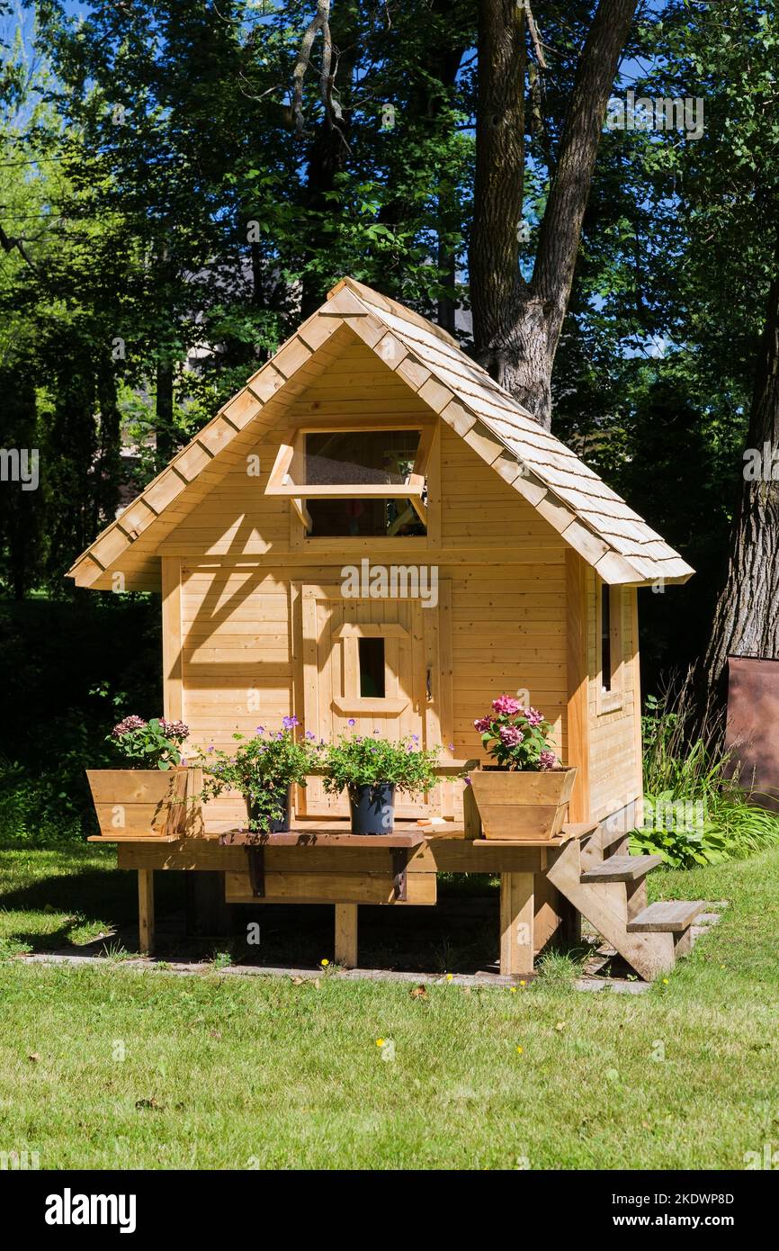 Children's pinewood playhouse facade with flowering plants on front