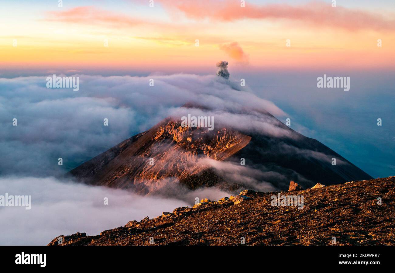 Volcan de Fuego in the clouds at sunrise seen from Acatenango. Guatemala. Stock Photo