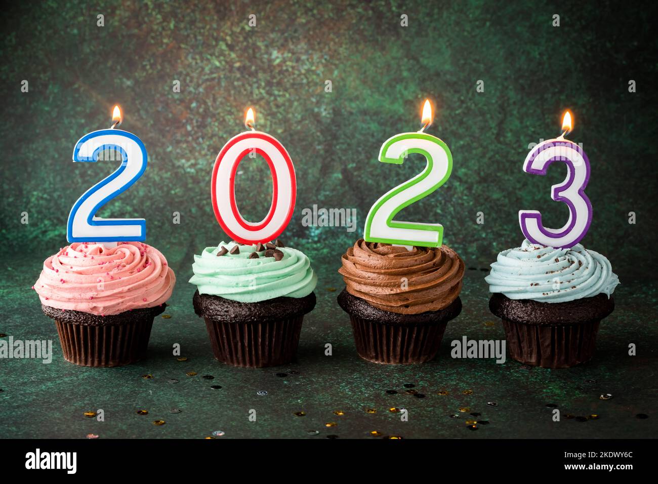 Large buttercream frosted cupcakes with lit number candles for the New Year. Stock Photo