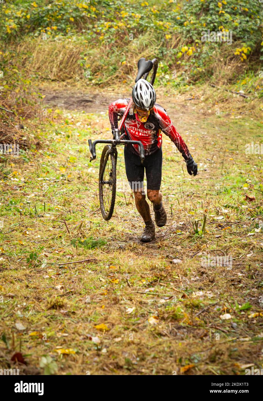 WA21419-00...WASHINGTON - Cyclocross racer carrying bike while running up a steep hill during the 2021 CRX race at Enumclaw. Stock Photo