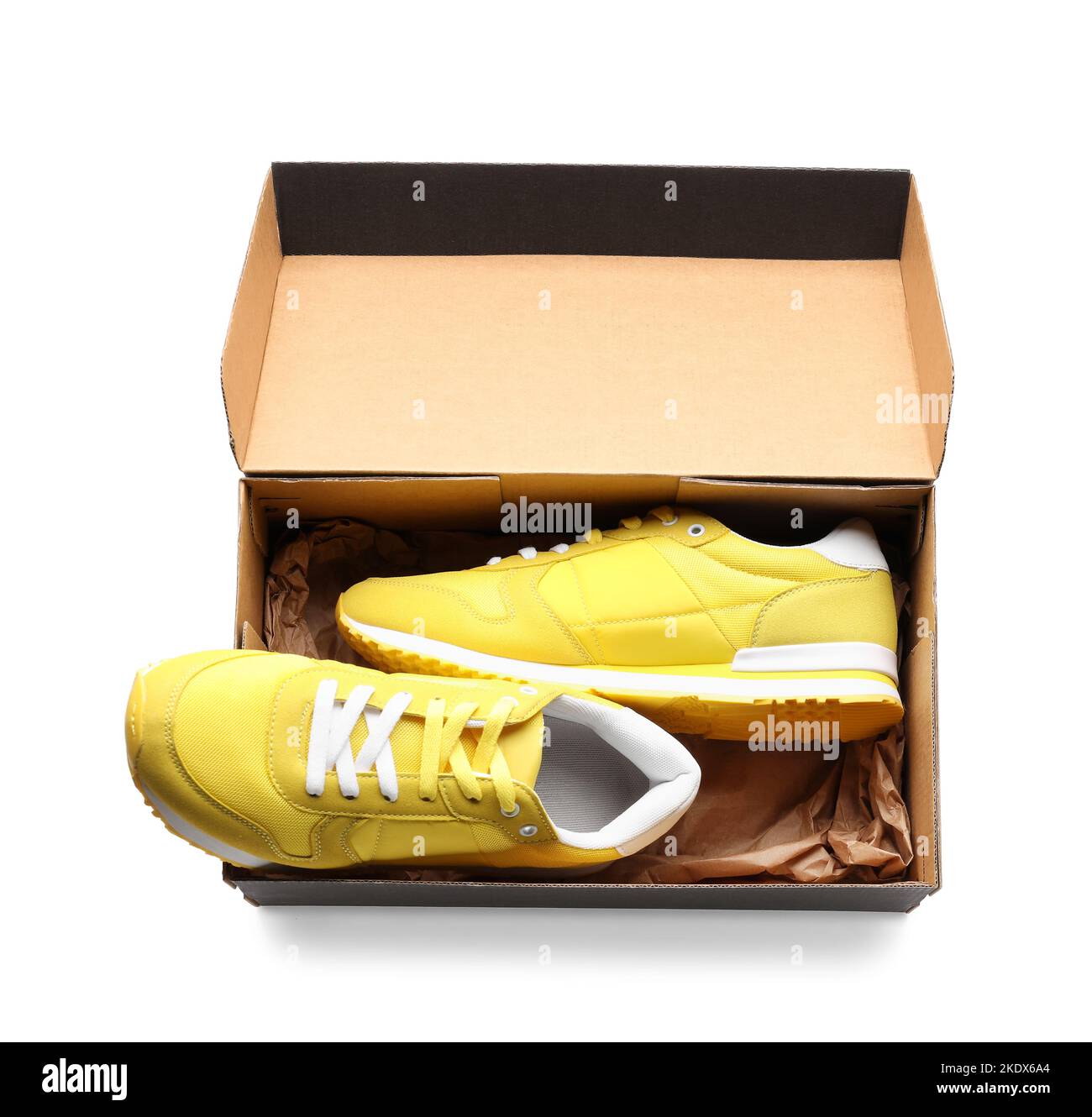 cardboard box with yellow sneakers on white background 2KDX6A4