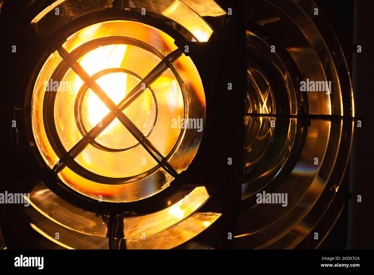 Glowing yellow lighthouse lamp with a Fresnel lens. It is a type of composite compact lens developed by the French physicist Augustin-Jean Fresnel for Stock Photo