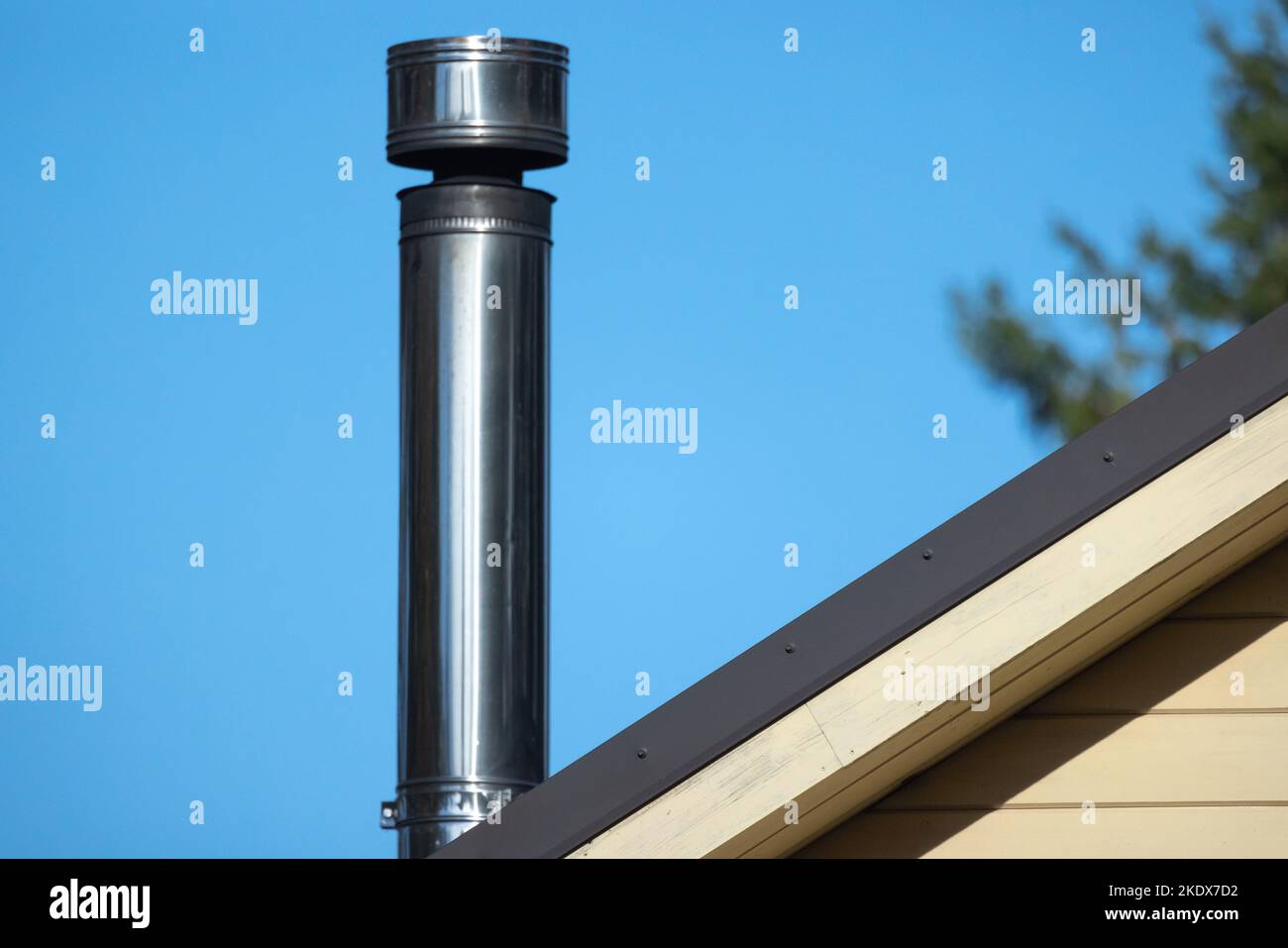 Round metal chimney is on a rural house roof Stock Photo