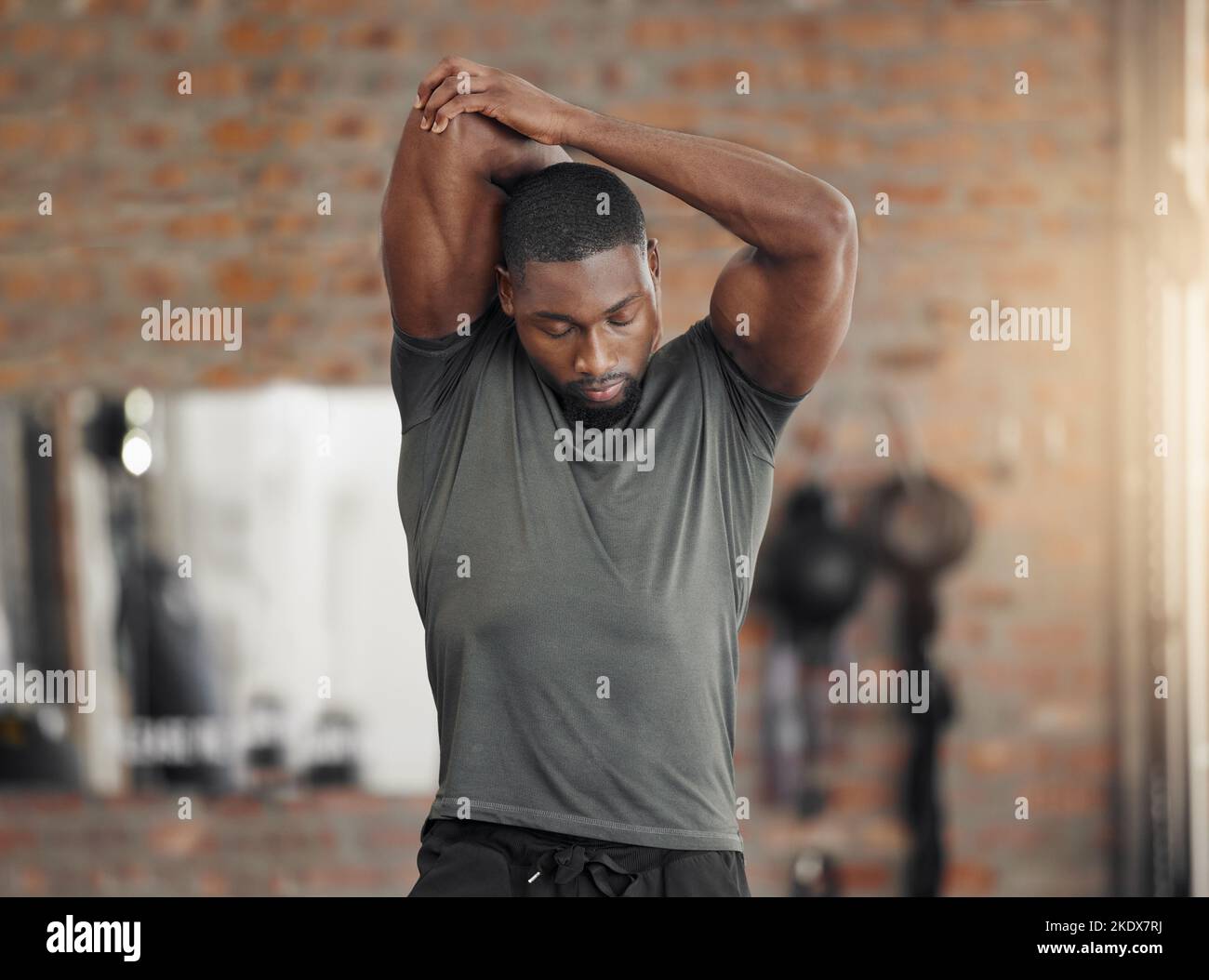Exercise, stretch and man at gym for training, health and wellness against a brick wall background mockup. Fitness, stretching and sport guy with Stock Photo