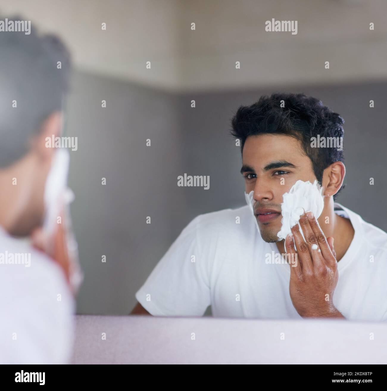 His daily facial fix up. a handsome young man shaving his facial hair