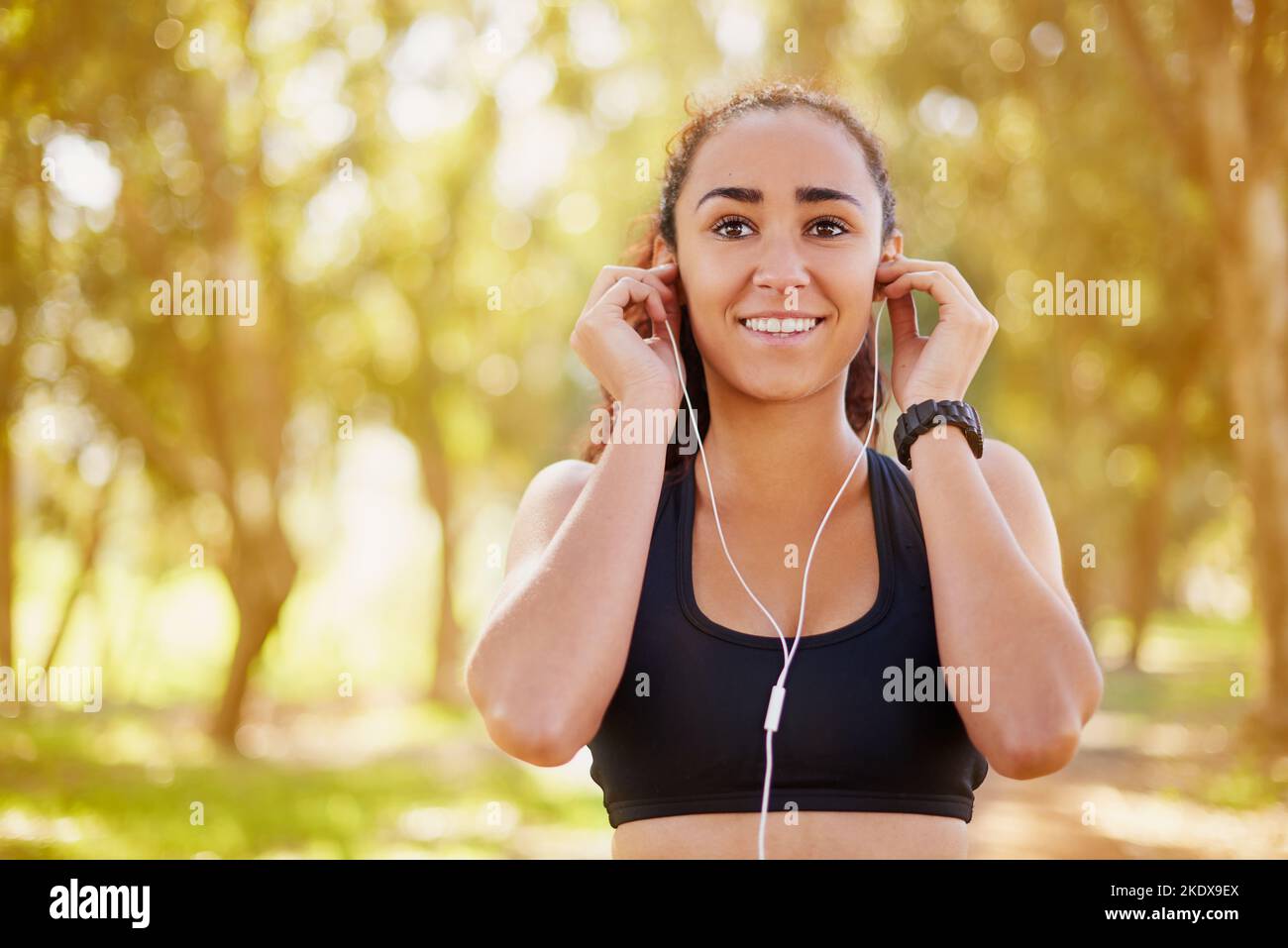 Outdoor workouts are awesome for your mood. a sporty young listening to music while working out outdoors. Stock Photo