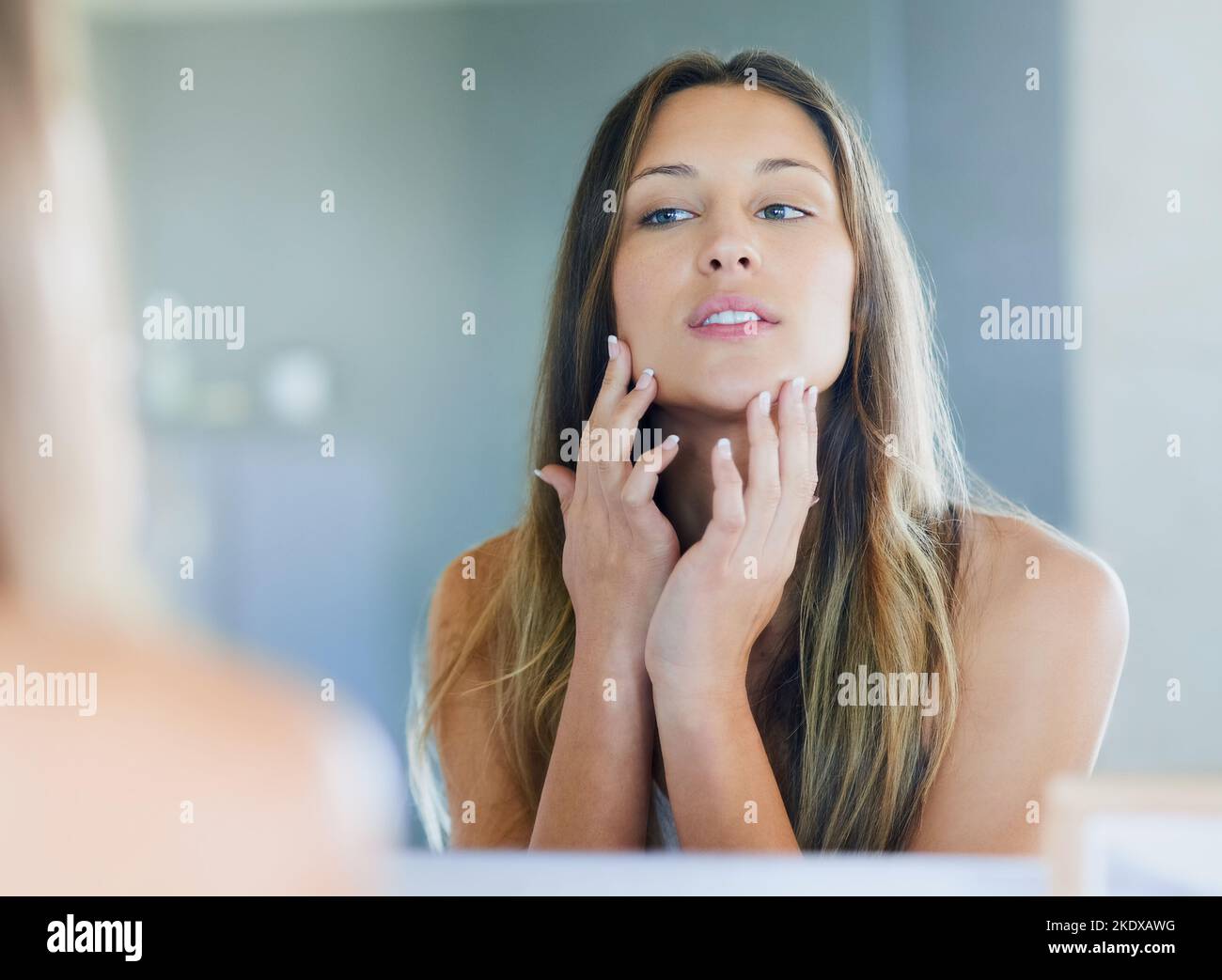 No imperfections allowed. a happy young woman examining her flawless