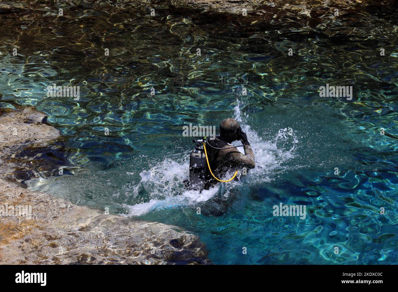 May 29, 2022, Larnaca, Cyprus: A scuba diver jumps into the blue lagoon of the Mediterranean Sea at Cape Greco National Forest Park at the southern end of Famagusta Bay and forms part of Ayia Napa Municipality. The Republic of Cyprus stands at a historic and cultural crossroads between Europe and Asia. Its chief cities-the capital of Nicosia, Limassol, Famagusta, and Paphos have absorbed the influences of generations of conquerors, pilgrims, and travelers and have an air that is both cosmopolitan and provincial. Today Cyprus is a popular tourist destination for visitors from Europe, favored by Stock Photo