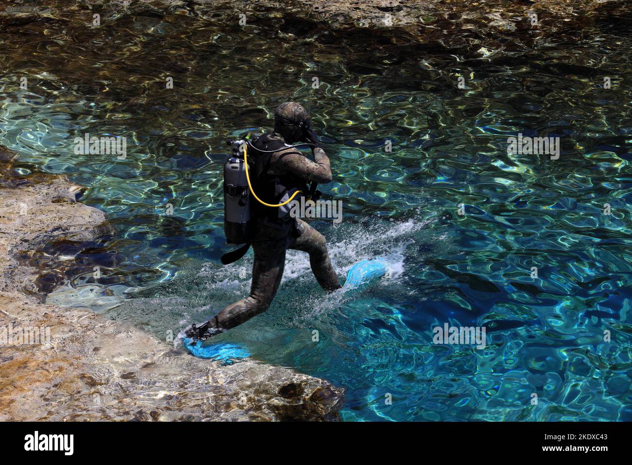 May 29, 2022, Larnaca, Cyprus: A scuba diver jumps into the blue lagoon of the Mediterranean Sea at Cape Greco National Forest Park at the southern end of Famagusta Bay and forms part of Ayia Napa Municipality. The Republic of Cyprus stands at a historic and cultural crossroads between Europe and Asia. Its chief cities-the capital of Nicosia, Limassol, Famagusta, and Paphos have absorbed the influences of generations of conquerors, pilgrims, and travelers and have an air that is both cosmopolitan and provincial. Today Cyprus is a popular tourist destination for visitors from Europe, favored by Stock Photo