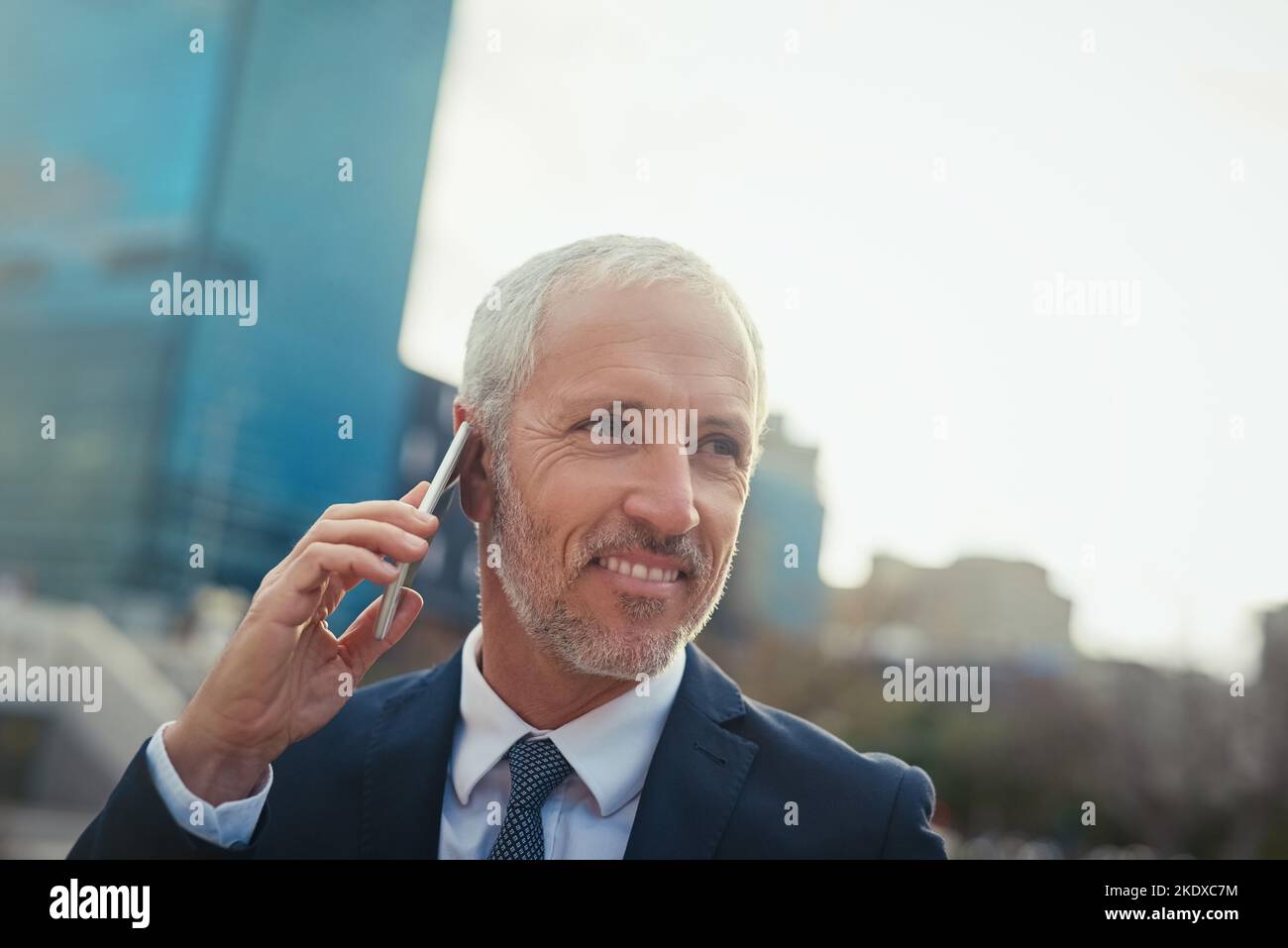 I call the shots around here. a businessman answering his phone while walking to his office in the city. Stock Photo