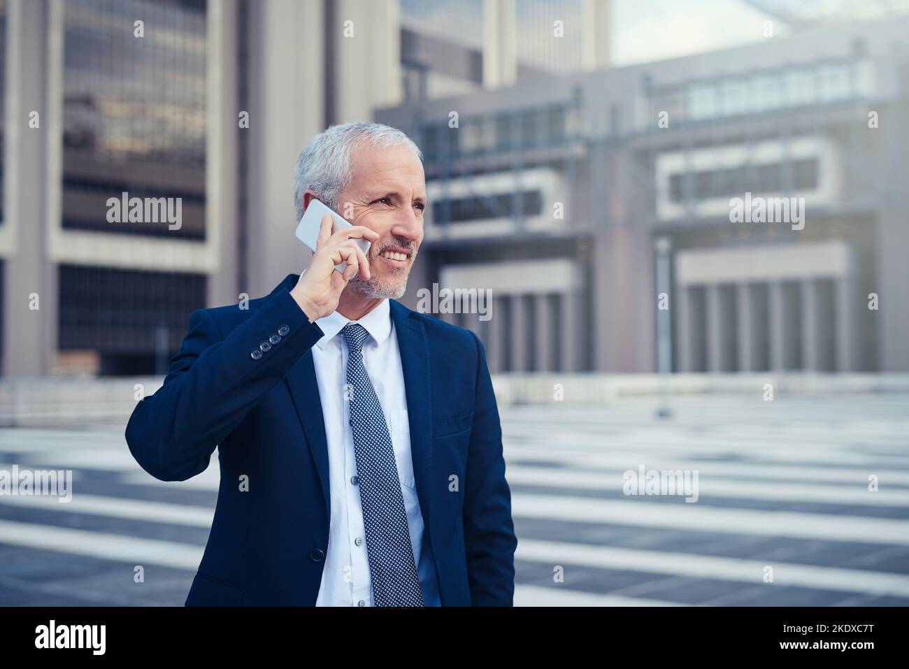 Hes a businessman on the move. a businessman answering his phone while walking to his office in the city. Stock Photo