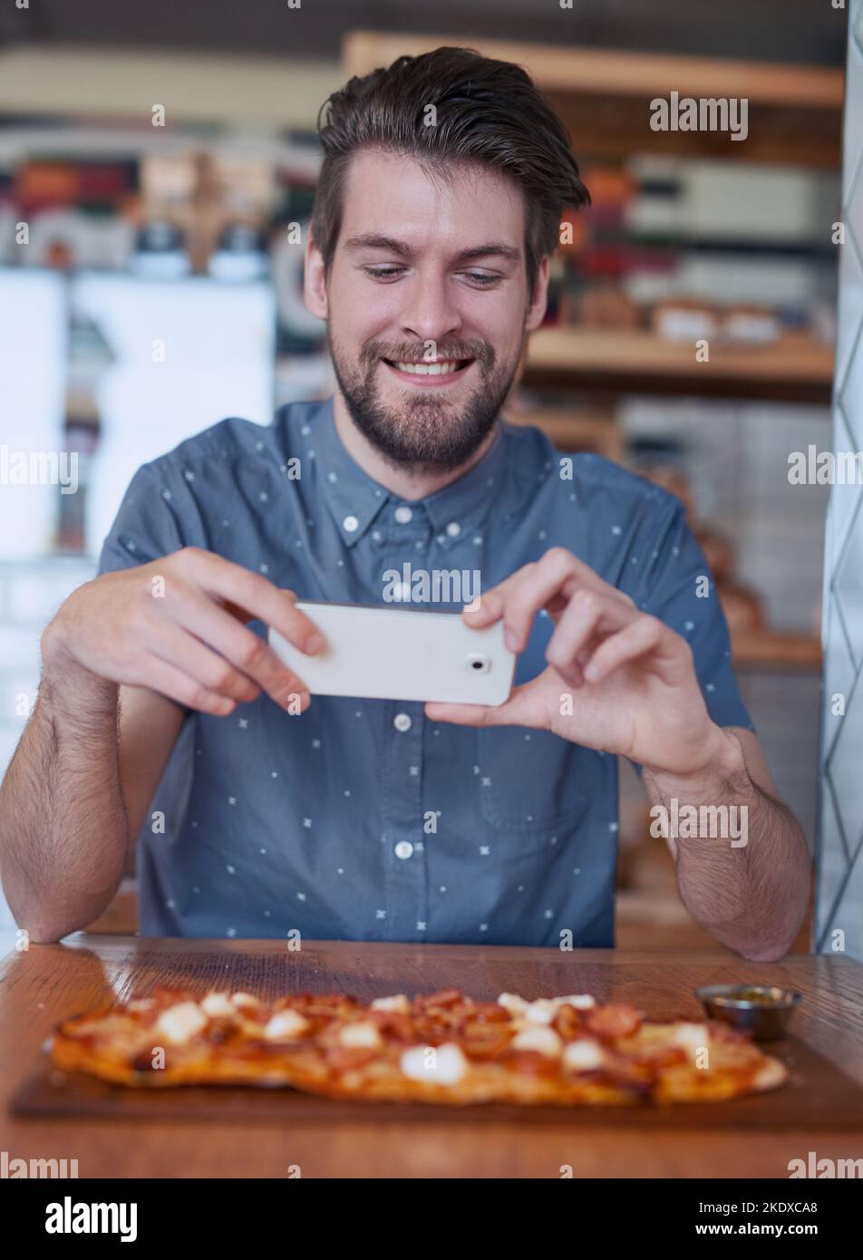 Straight to social media. a man taking a picture of his food at a restaurant. Stock Photo