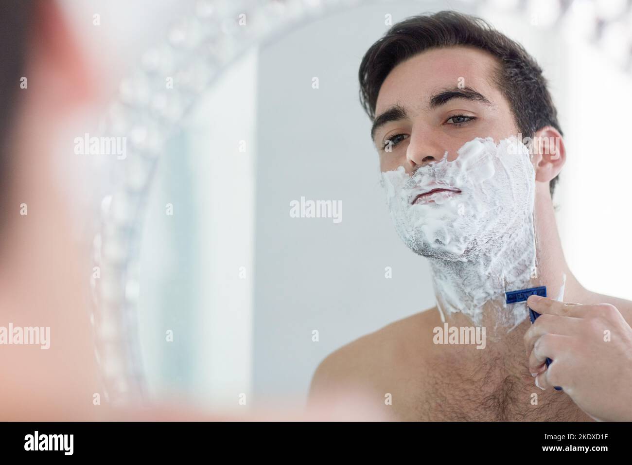 No beard, no problem. a young man shaving his facial hair in the