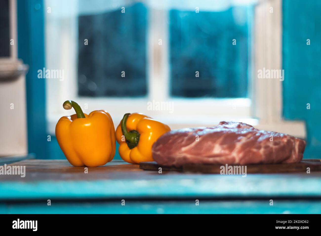 fresh meat and yellow peppers in a blue kitchen Stock Photo