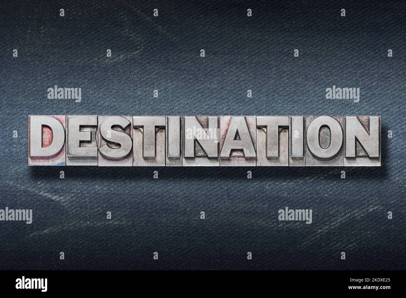 destination word made from metallic letterpress on dark jeans background Stock Photo