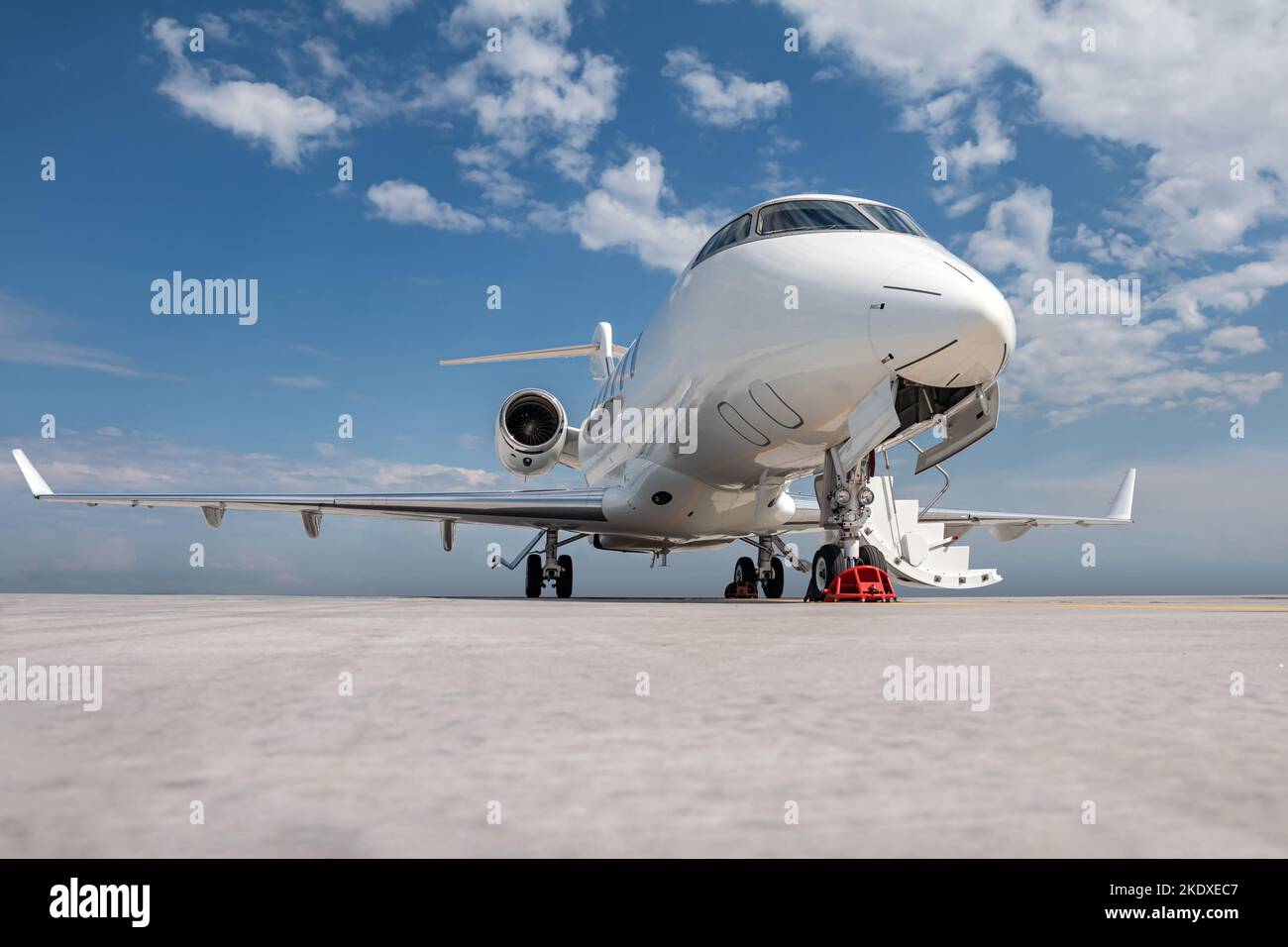 Modern white executive airplane with an opened gangway door at the airport apron Stock Photo