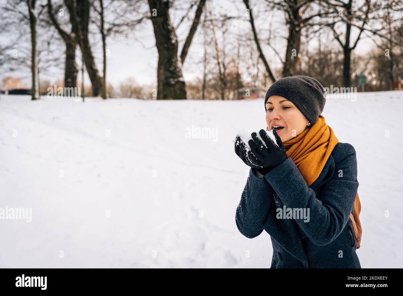 A woman blows snow off her palms in winter. Stock Photo