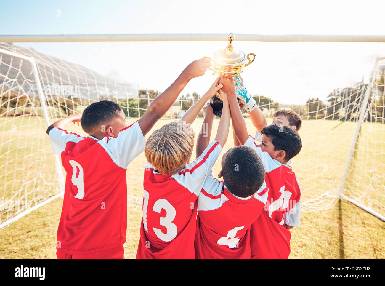 Children, winner and team soccer with trophy celebrating victory, achievement or match on the field. Kids in celebration for teamwork, sports and Stock Photo