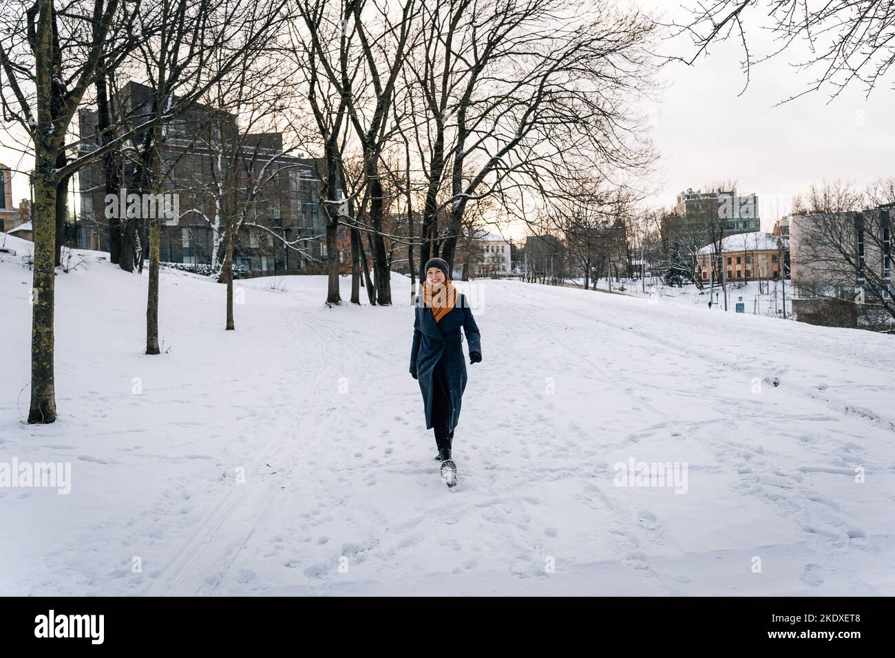 Wide viewing angle on a woman walking through a snowy winter city. Stock Photo