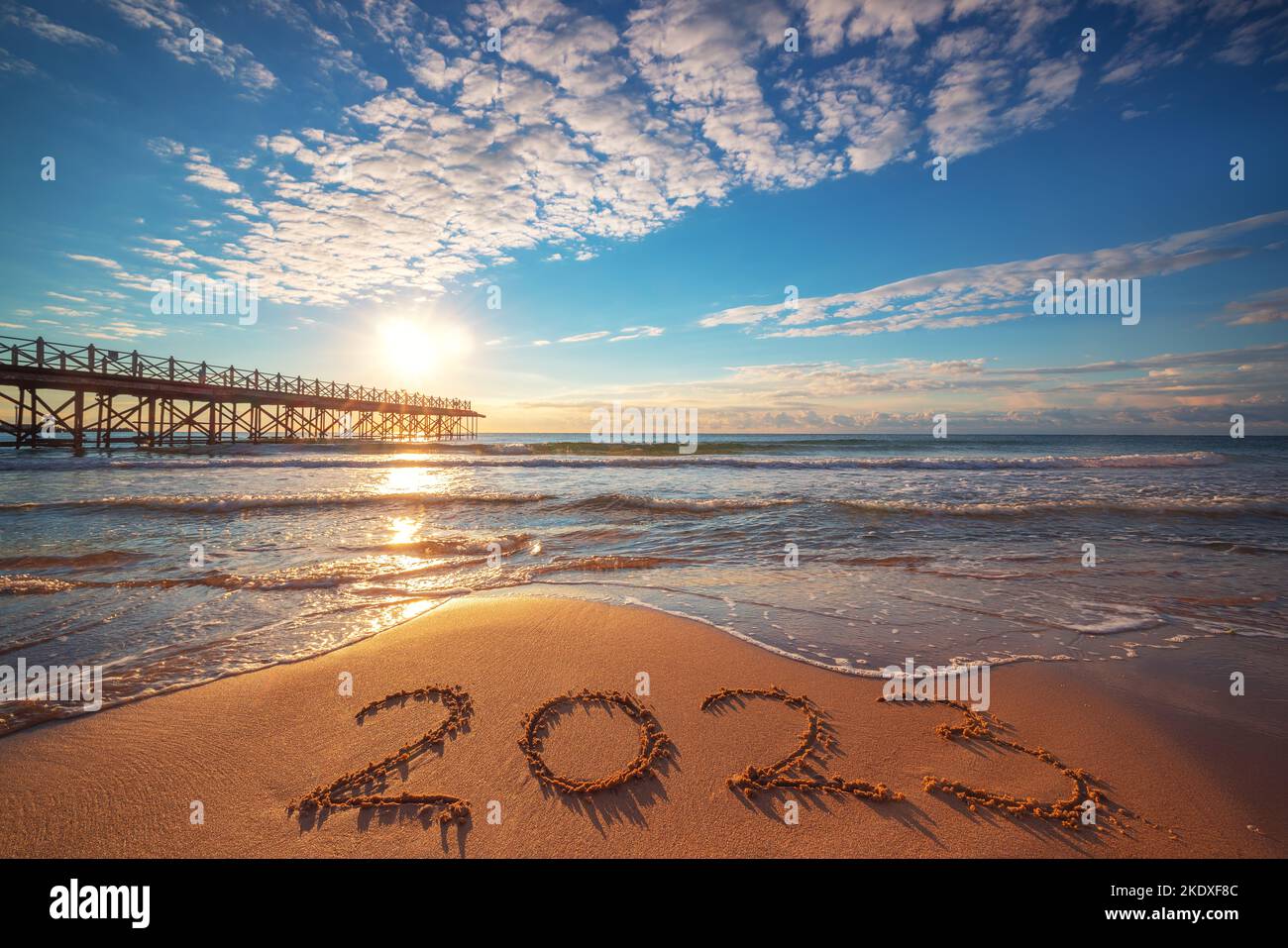 Happy New Year 2023 concept, lettering on the beach. Written text on the sea beach at sunrise. Stock Photo