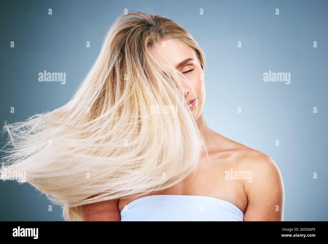 Hair care, young woman and with natural beauty, happy and treatment for cosmetics, pride and with blue studio background. Hair flip, girl or female Stock Photo