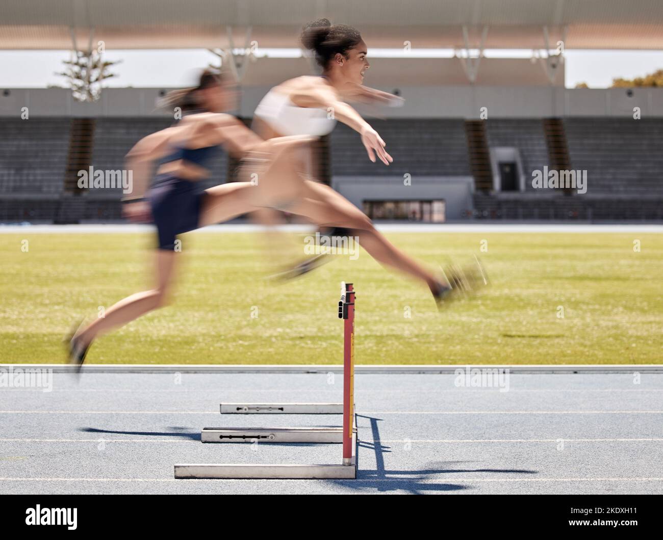 Woman, sports and hurdle athletics running for exercise, training or workout at the stadium track outdoors. Fitness women athletes in competitive Stock Photo