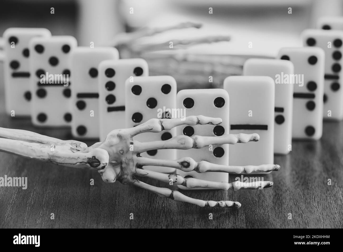 Skeleton hand and domino bones are on the table, black and white photo, death game, gambling Stock Photo