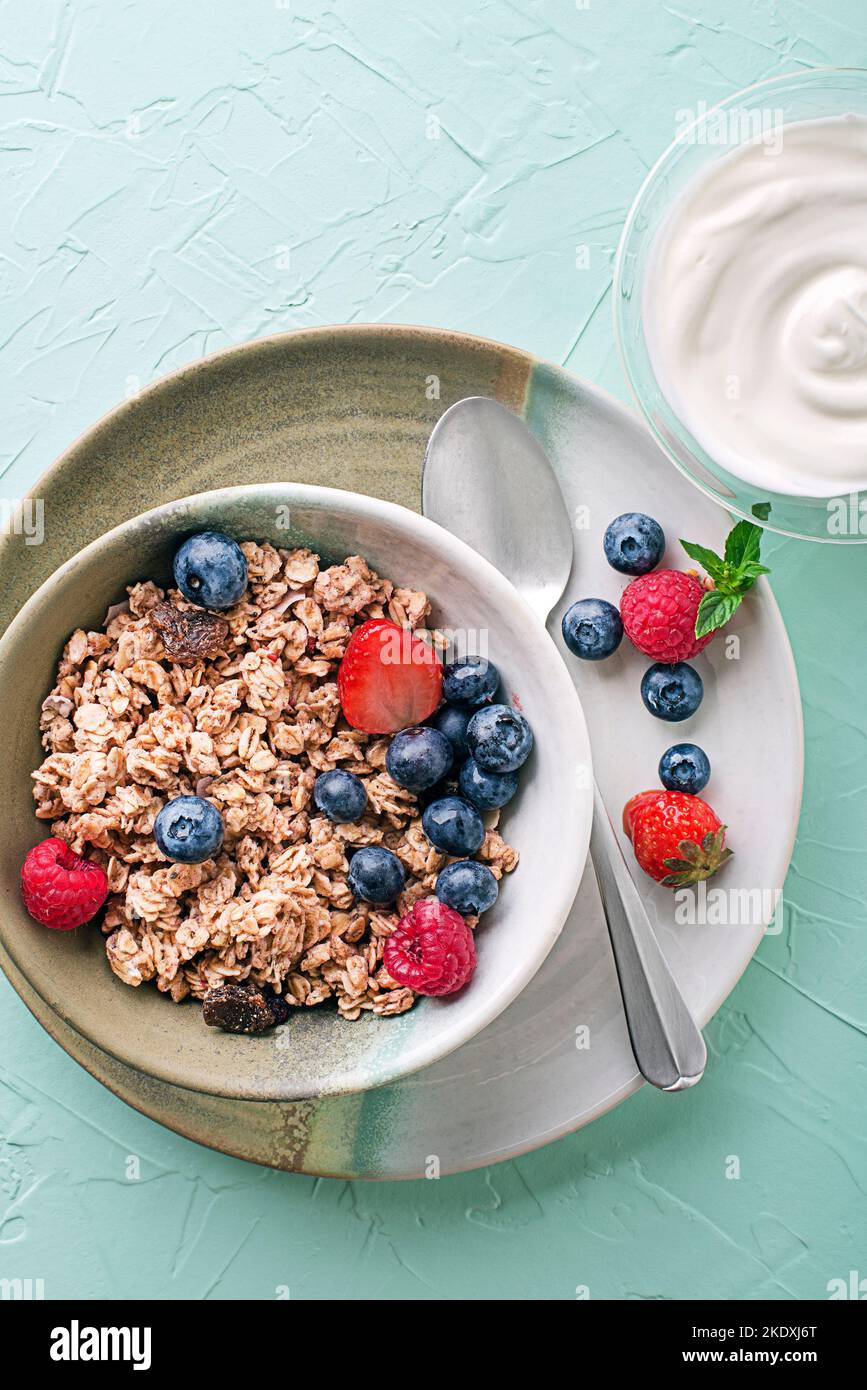 A bowl of dry granola served with fresh berry fruit and yogurt. Oatmeal plate. Healthy food, diet. Top view. Stock Photo