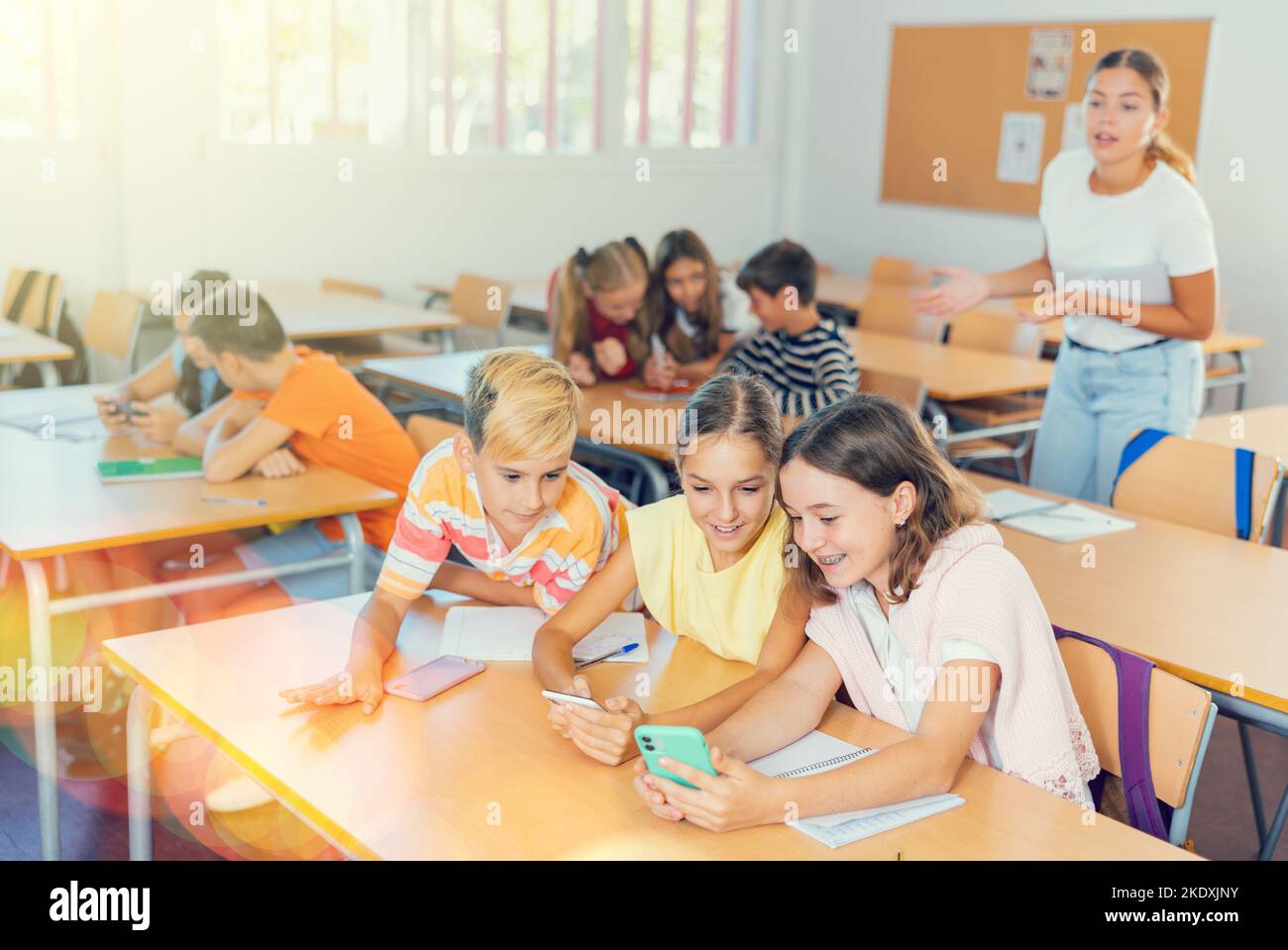 Group of kids using smartphones during lesson in school Stock Photo - Alamy