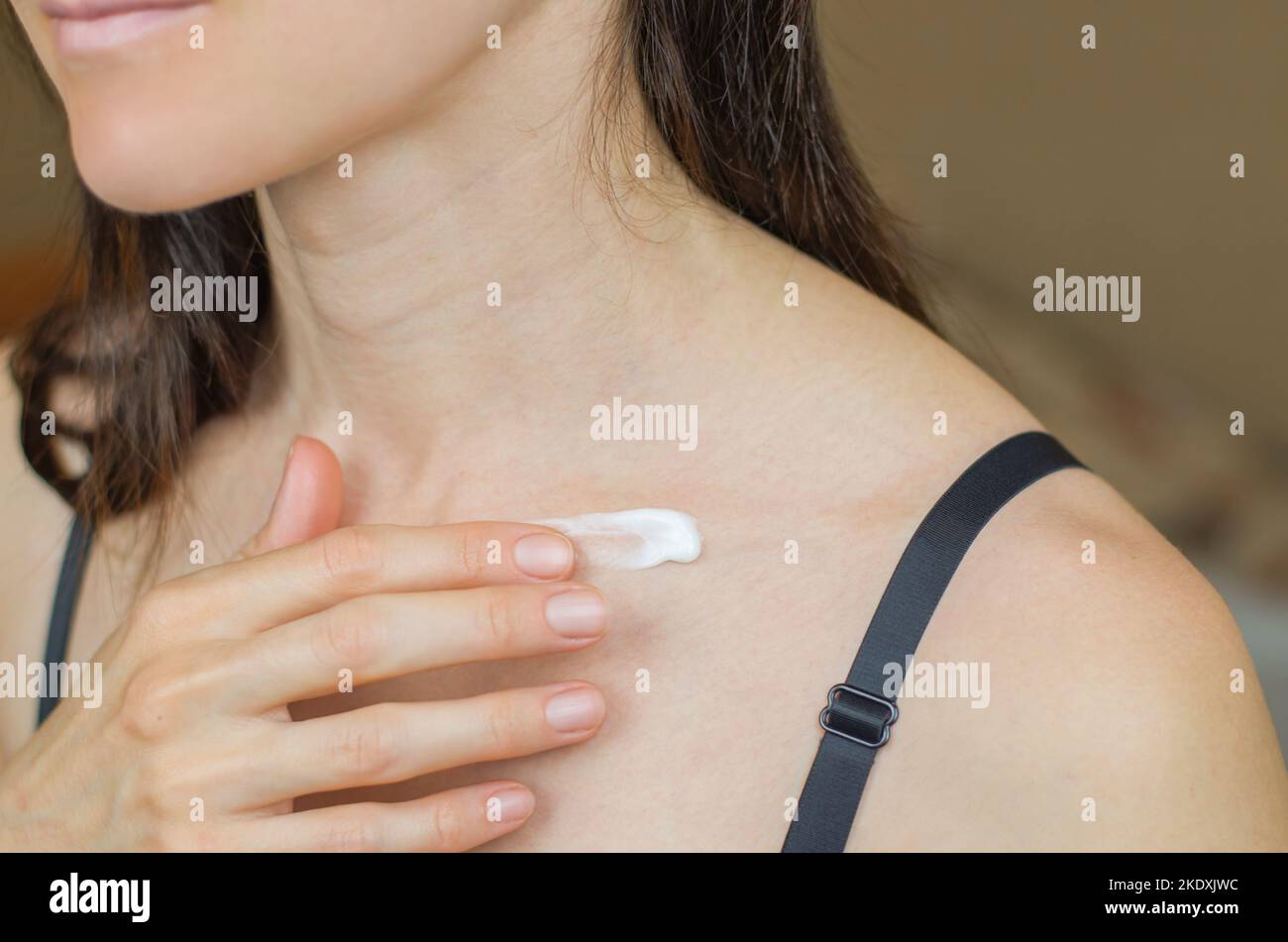 Close-up of a woman applying moisturizer to her collarbone. Woman applying moisturizer to body Stock Photo
