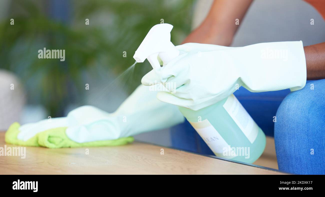 Hands, table and cleaning during covid by woman sanitize, spray and