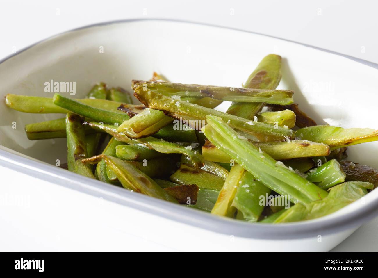 Green beans, fried in olive oil and seasoned with sea salt, in an enamel dish bowl Stock Photo