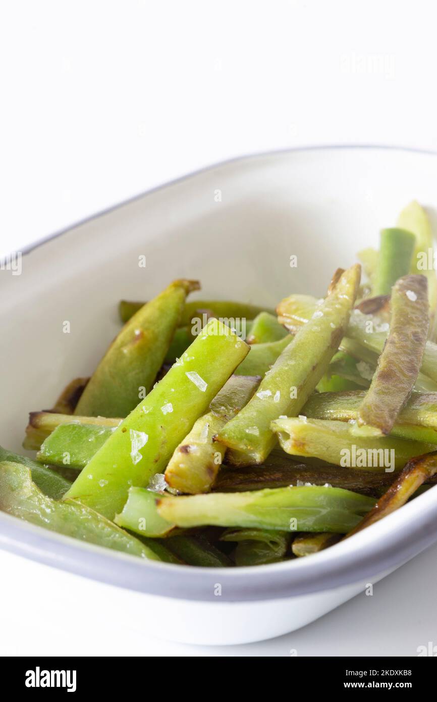 Green beans, fried in olive oil and seasoned with sea salt, in an enamel dish bowl Stock Photo