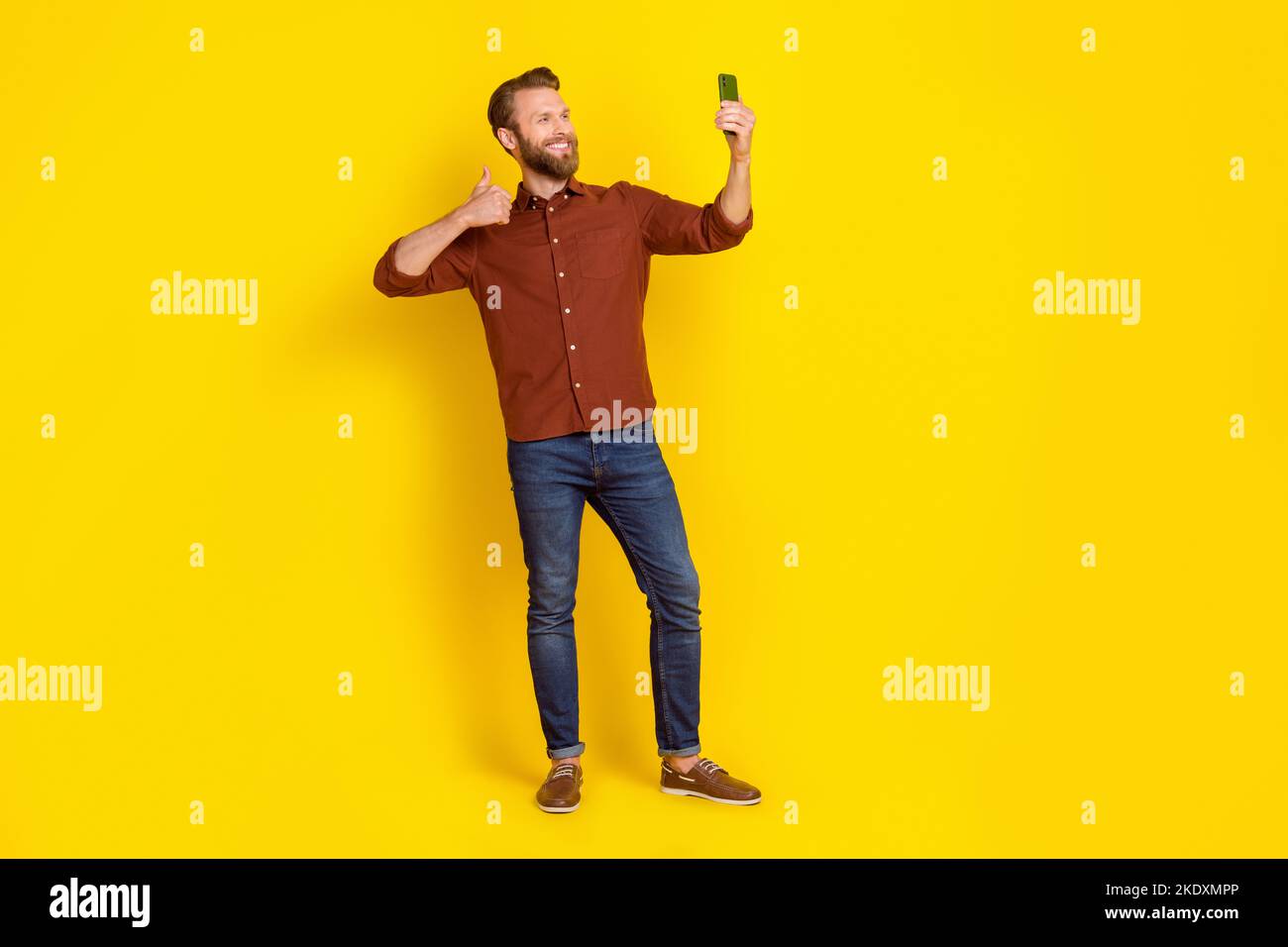 Full body of positive attractive guy hold telephone take selfie show thumb up isolated on yellow color background Stock Photo