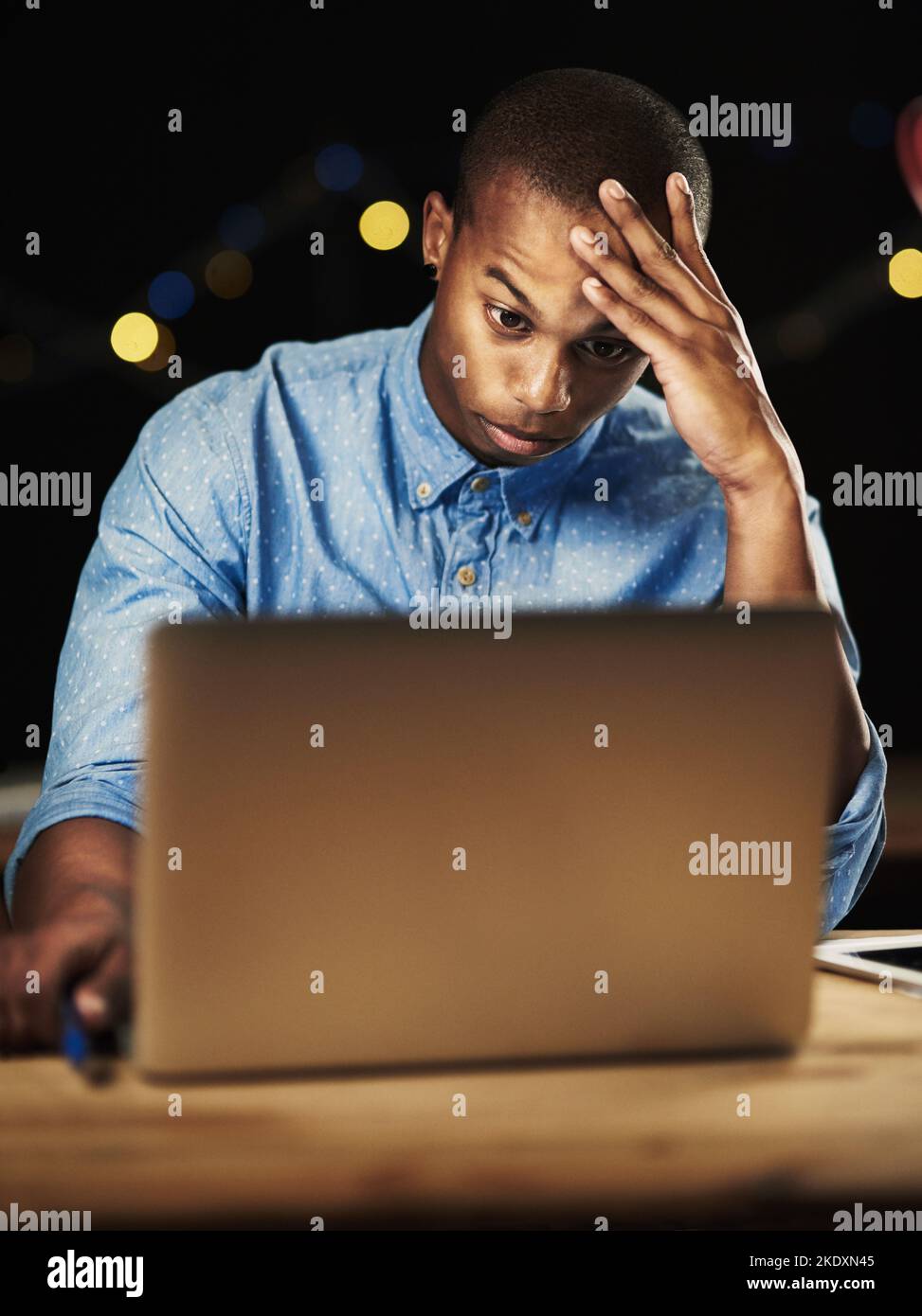 The deadline is looming. a young man looking stressed while working late night on his laptop. Stock Photo