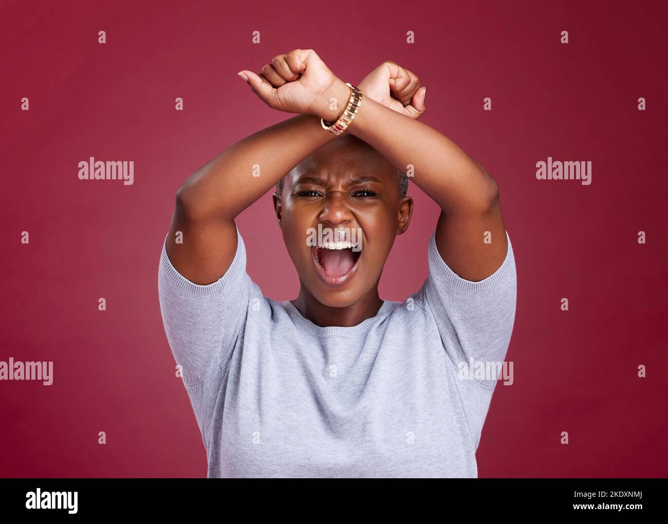 Black woman, shouting and protest to stop racism or discrimination against a red studio background. Angry African American female voice with arms Stock Photo